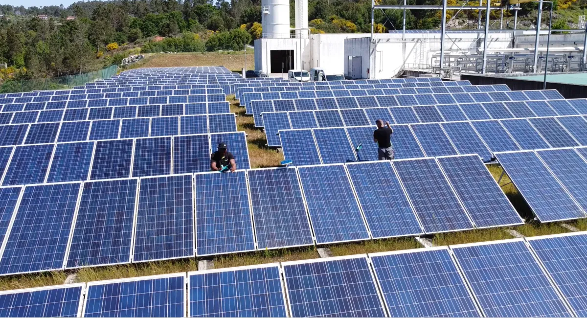 Vista aérea de uma instalação fotovoltaica de grande dimensão, com técnicos da Enbiente no local